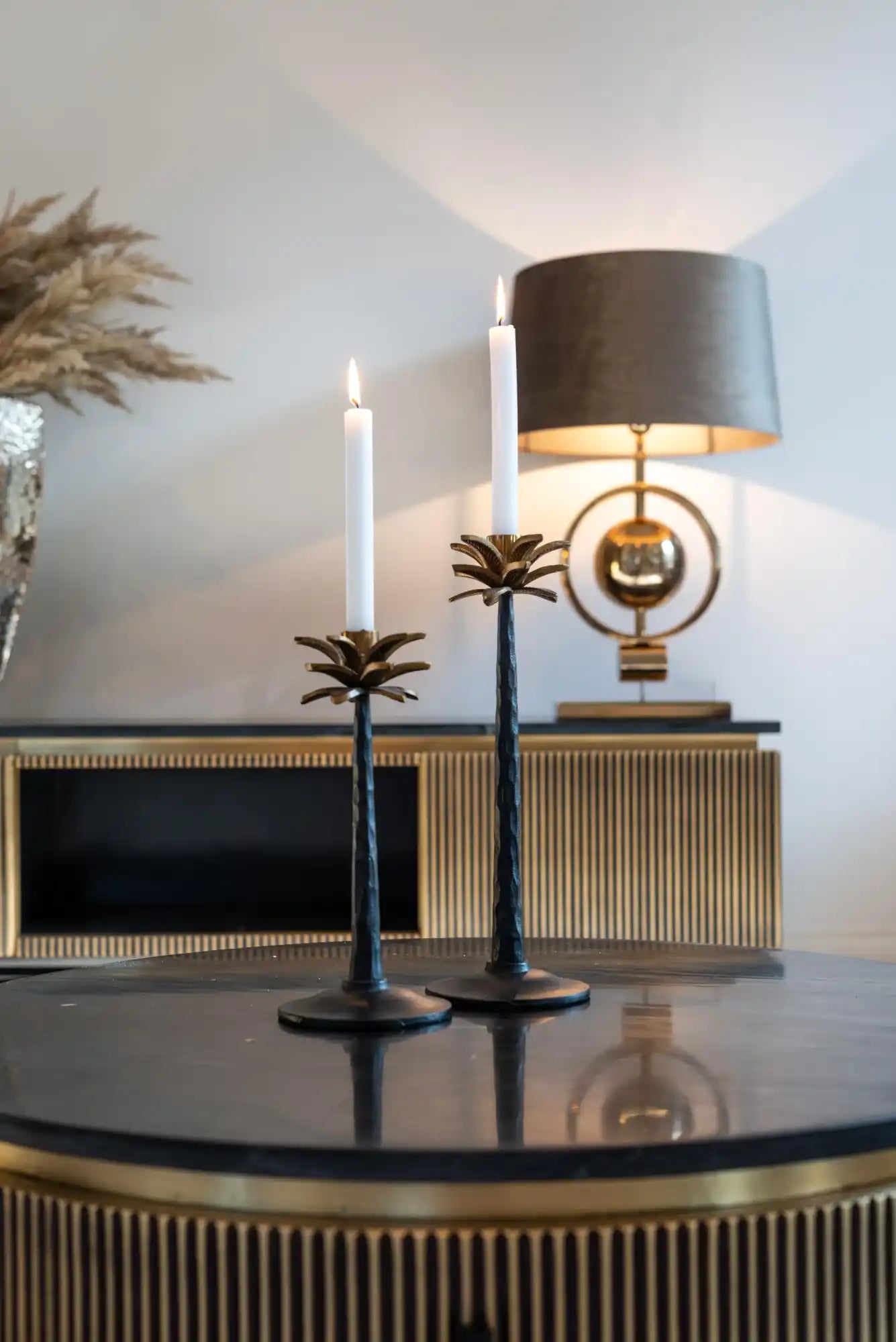 Two black palm tree-shaped candle holders with lit white candles.
